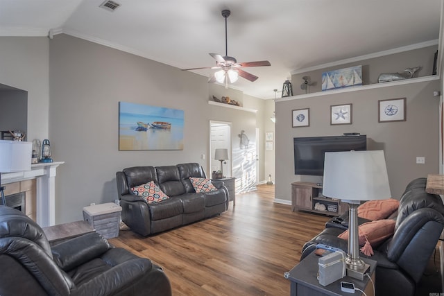 living room with visible vents, ceiling fan, vaulted ceiling, ornamental molding, and wood finished floors