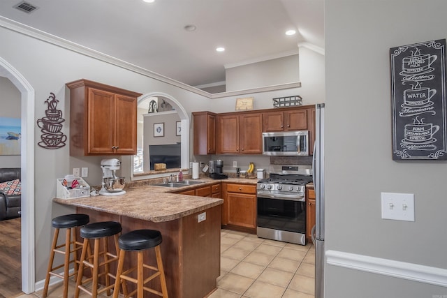 kitchen with visible vents, a sink, stainless steel appliances, arched walkways, and a peninsula