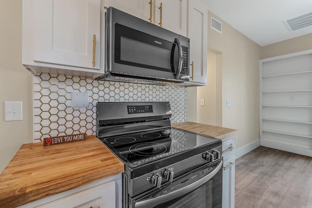 kitchen featuring visible vents, wooden counters, and black electric range