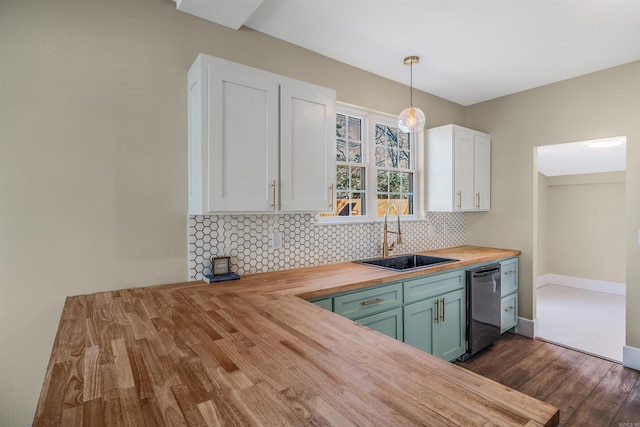 kitchen with wooden counters, a sink, decorative backsplash, white cabinets, and stainless steel dishwasher