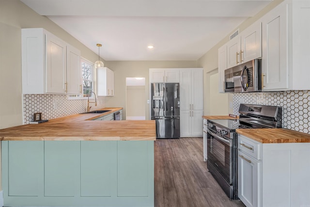 kitchen featuring visible vents, dark wood finished floors, butcher block counters, stainless steel appliances, and a sink