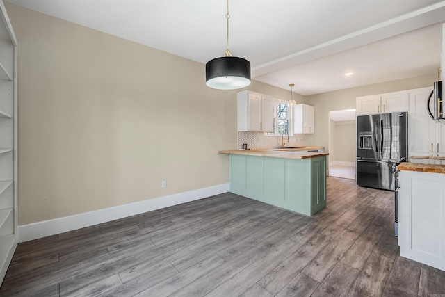 kitchen with backsplash, wooden counters, a peninsula, black fridge with ice dispenser, and a sink