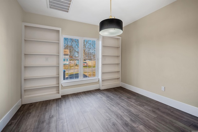 unfurnished dining area with visible vents, baseboards, and wood finished floors