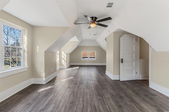 additional living space featuring visible vents, plenty of natural light, dark wood-type flooring, and ceiling fan