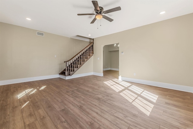 unfurnished living room with light wood finished floors, visible vents, baseboards, stairs, and a ceiling fan