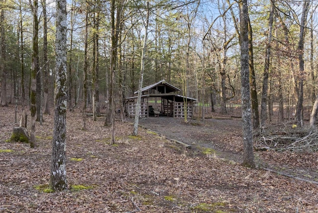 exterior space with a forest view, an outdoor structure, and a pole building