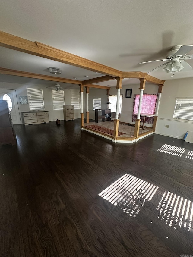 interior space featuring baseboards, decorative columns, beam ceiling, wood finished floors, and a ceiling fan