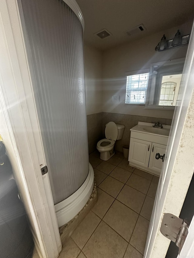 half bath with tile patterned floors, visible vents, toilet, and vanity