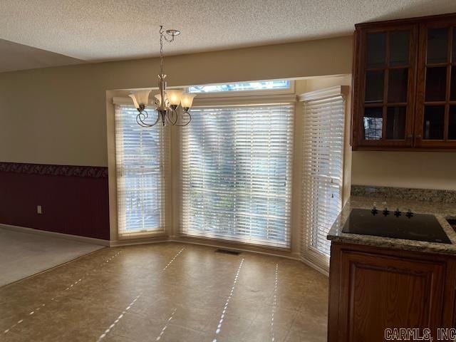 unfurnished dining area with a textured ceiling and a chandelier