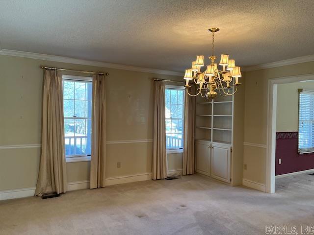 unfurnished dining area with light carpet, a notable chandelier, ornamental molding, and a textured ceiling