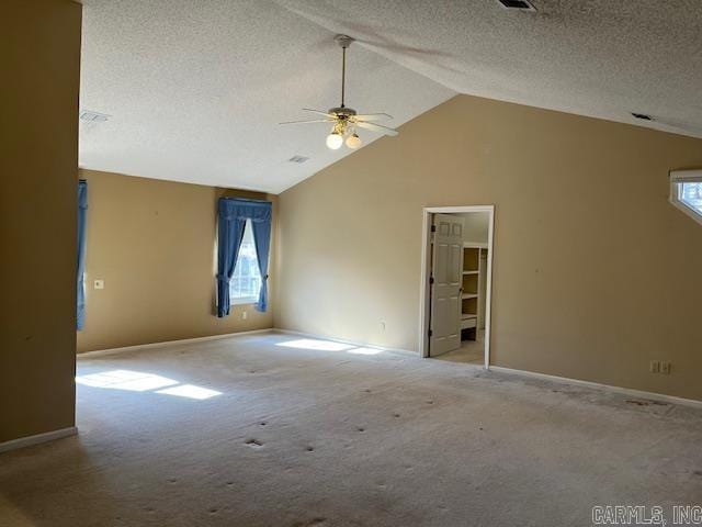 carpeted spare room featuring baseboards, lofted ceiling, a textured ceiling, and a ceiling fan