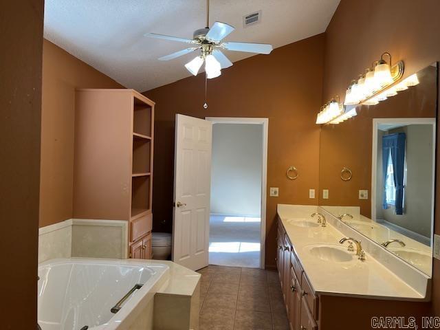 full bath with a sink, ceiling fan, tile patterned flooring, and vaulted ceiling