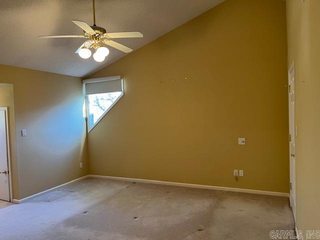 unfurnished room with carpet flooring, ceiling fan, baseboards, and lofted ceiling