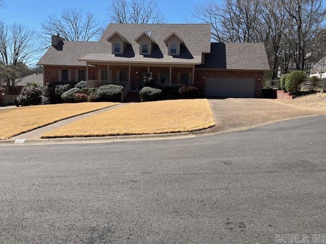 cape cod house with a porch, an attached garage, and driveway