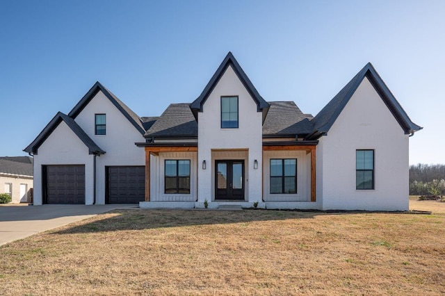 modern farmhouse featuring brick siding, a front lawn, french doors, driveway, and an attached garage