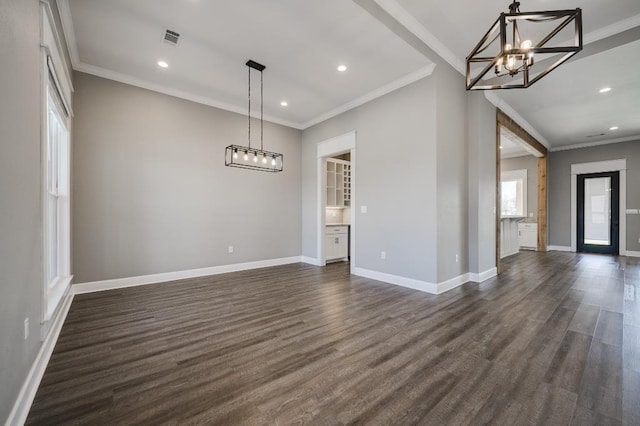 unfurnished dining area with visible vents, a notable chandelier, ornamental molding, baseboards, and dark wood-style flooring