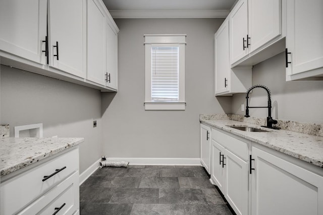 laundry area with cabinet space, baseboards, hookup for an electric dryer, and a sink