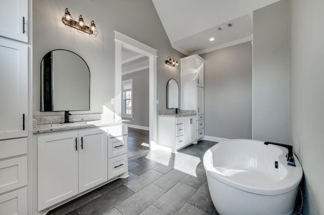 full bath featuring visible vents, ornamental molding, two vanities, a freestanding tub, and a sink