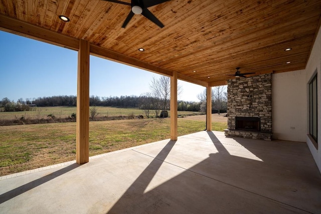 view of patio featuring a rural view, an outdoor stone fireplace, and ceiling fan