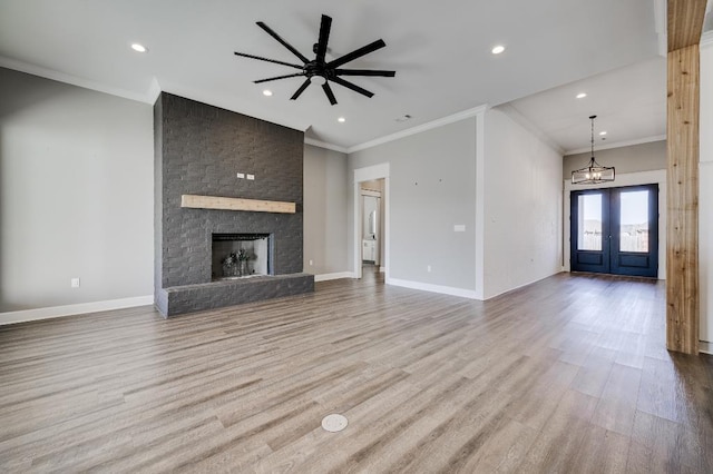 unfurnished living room featuring ceiling fan with notable chandelier, crown molding, baseboards, and wood finished floors