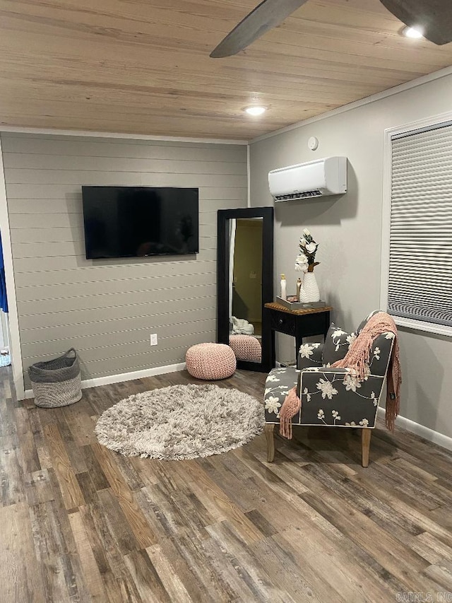 living area with baseboards, an AC wall unit, wood finished floors, and wooden ceiling