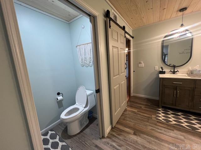 bathroom featuring vanity, wood finished floors, baseboards, wood ceiling, and toilet