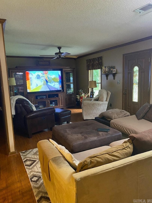 living room with a ceiling fan, wood finished floors, visible vents, and a textured ceiling