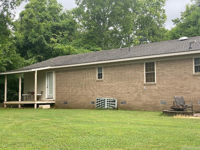 rear view of house with crawl space, brick siding, and a yard