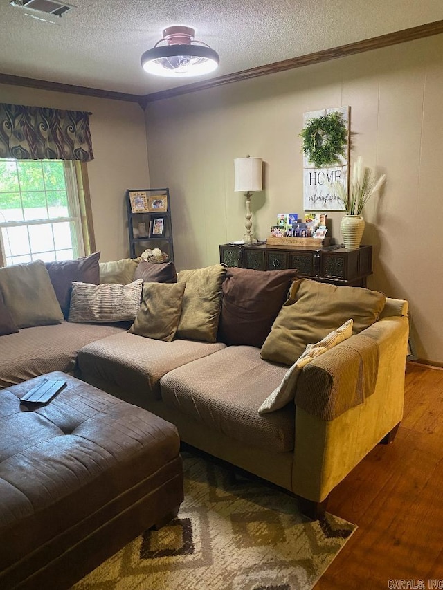 living room with crown molding, wood finished floors, visible vents, and a textured ceiling