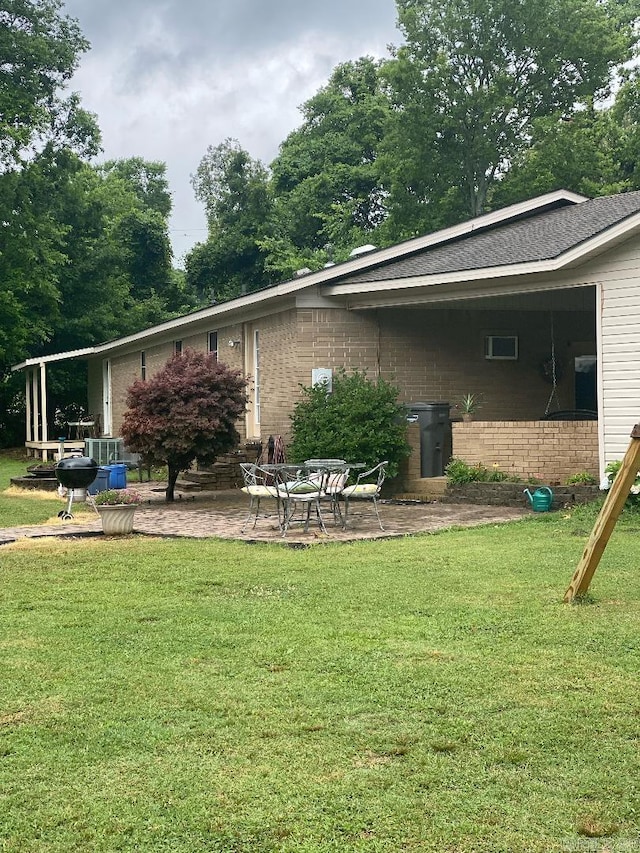 back of house with a lawn, brick siding, and a patio area