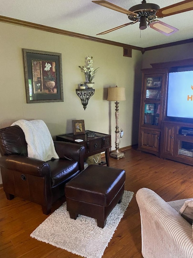 living area featuring a textured ceiling, crown molding, a ceiling fan, and wood finished floors