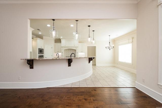 kitchen with a breakfast bar, light stone counters, light wood-type flooring, and stainless steel appliances