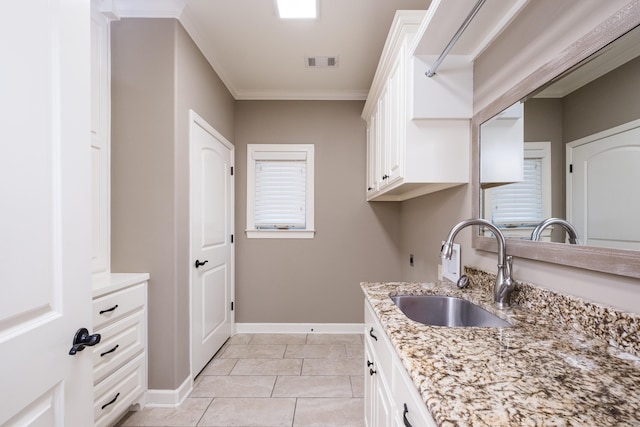 kitchen featuring visible vents, ornamental molding, a sink, light stone counters, and baseboards