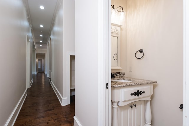 hall with a sink, crown molding, baseboards, recessed lighting, and dark wood-style flooring