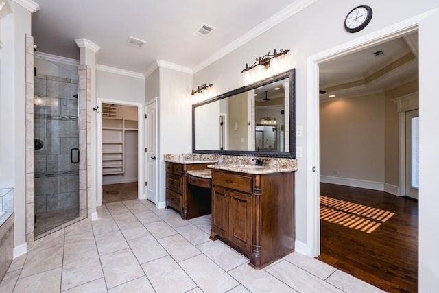 full bath featuring visible vents, baseboards, a stall shower, a walk in closet, and crown molding