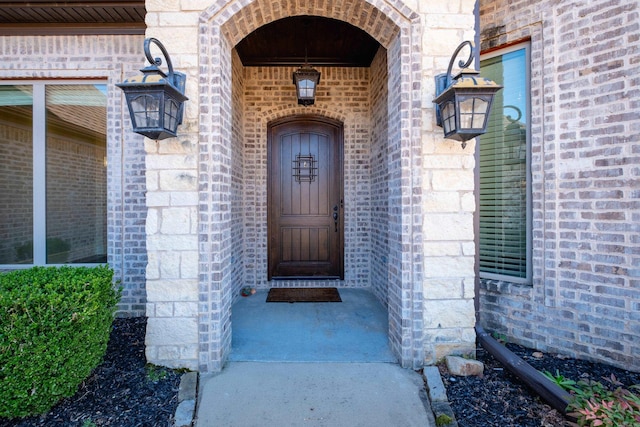 view of exterior entry featuring brick siding and stone siding