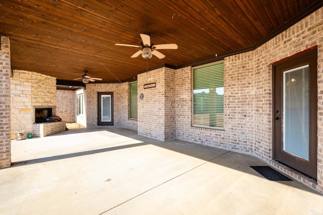 view of patio with ceiling fan and an outdoor stone fireplace