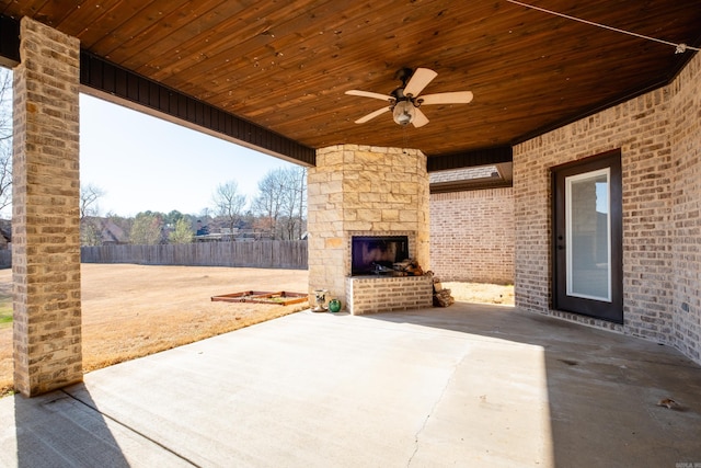 view of patio with ceiling fan, fence, and an outdoor stone fireplace