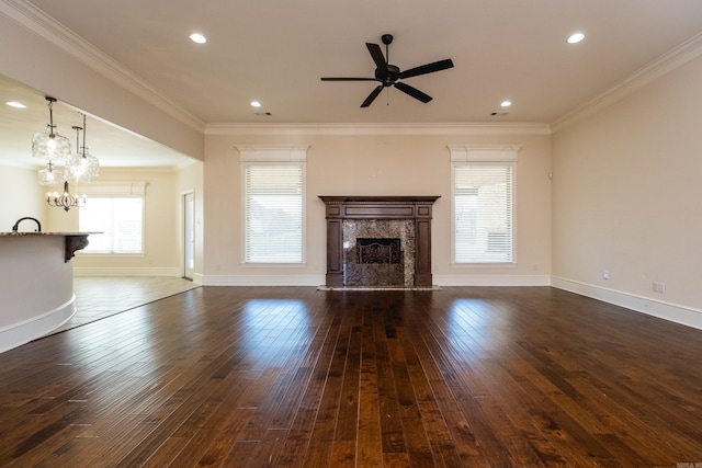 unfurnished living room with ornamental molding, dark wood finished floors, a high end fireplace, and ceiling fan with notable chandelier