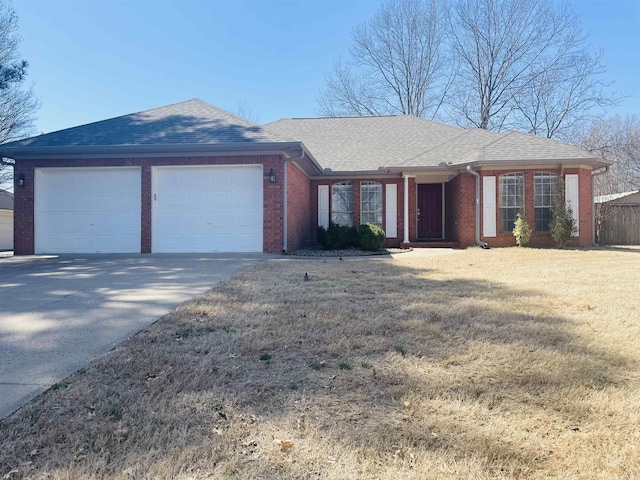 ranch-style house with a front yard, an attached garage, a shingled roof, concrete driveway, and brick siding