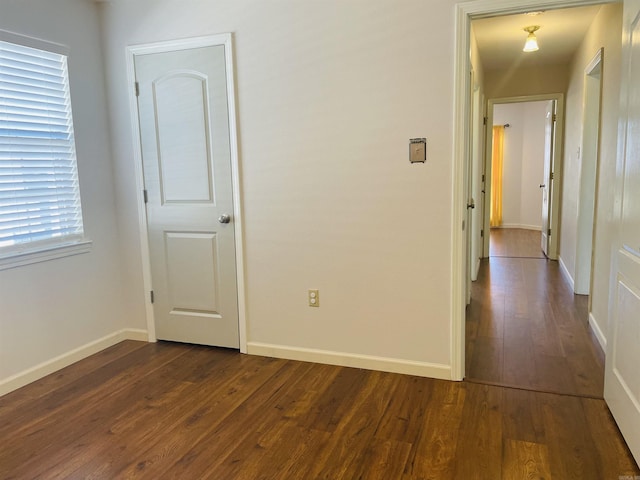 interior space with baseboards and dark wood-style flooring