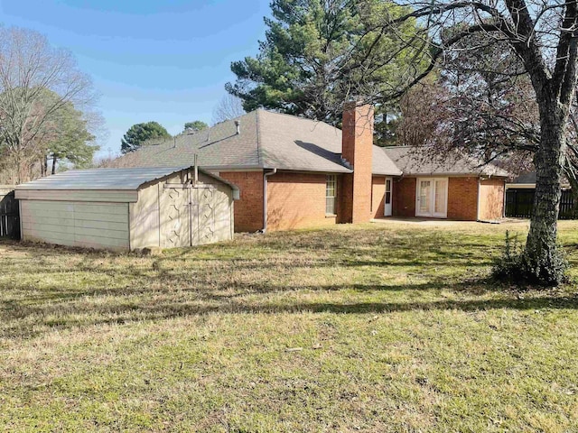 exterior space with an outbuilding, a lawn, a storage shed, a shingled roof, and a chimney