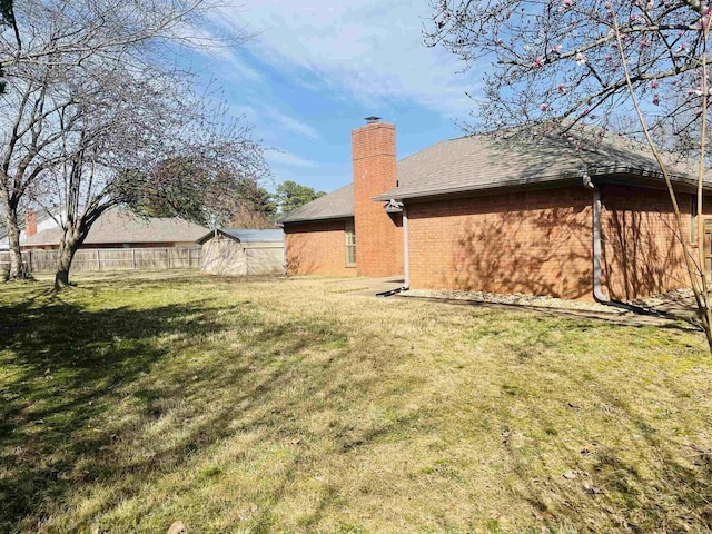 view of yard with an outbuilding, a storage unit, and fence