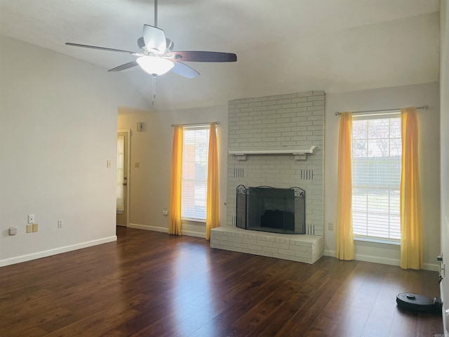 unfurnished living room with a ceiling fan, wood finished floors, baseboards, a brick fireplace, and vaulted ceiling