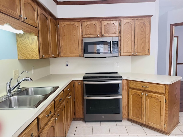 kitchen with brown cabinets, a sink, stainless steel appliances, a peninsula, and light countertops