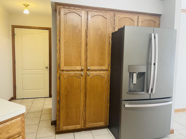 kitchen with light tile patterned floors, brown cabinets, light countertops, and stainless steel refrigerator with ice dispenser