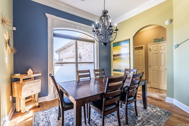 dining space featuring arched walkways, a notable chandelier, crown molding, and wood finished floors