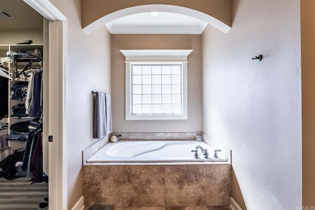 full bathroom featuring a spacious closet, visible vents, a bath, and ornamental molding