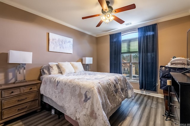 bedroom featuring visible vents, dark wood-type flooring, ornamental molding, a ceiling fan, and baseboards