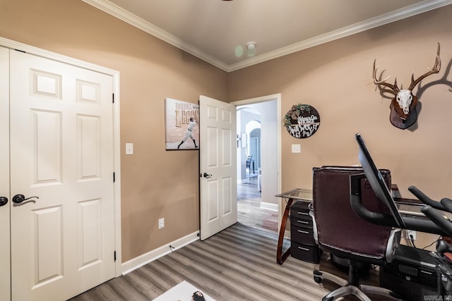 office featuring crown molding, wood finished floors, arched walkways, and baseboards